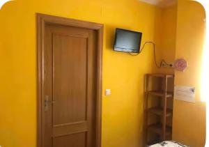 una habitación con una puerta y un televisor en una pared amarilla en Casa con encanto 1y perritos, en San Juan de Alicante