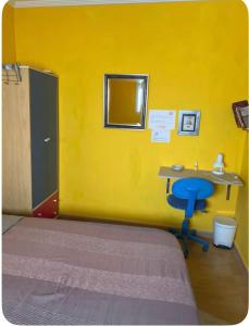 una habitación amarilla con una mesa y una silla azul en Casa con encanto 1y perritos, en San Juan de Alicante