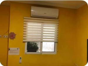 Una ventana en una habitación amarilla con una persiana en Casa con encanto 1y perritos, en San Juan de Alicante