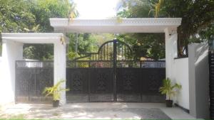 an entrance to a black gate with two potted plants at Mangroven River View Hotel in Bentota
