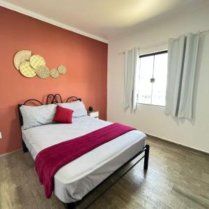 Schlafzimmer mit einem Bett mit roten Wänden und einem Fenster in der Unterkunft Studio no Centro com ESTACIONAMENTO GRÁTIS in Poços de Caldas