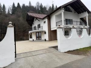 ein weißes Haus mit einem Balkon und einer Auffahrt in der Unterkunft Pensiunea Seraris in Voineasa