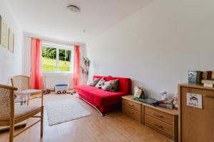 Una sala de estar con un sofá rojo y una ventana. en Ferienhof Schaubmeier, en Klaffer am Hochficht