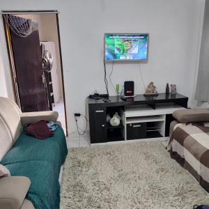 a living room with a couch and a flat screen tv at Casa com piscina Mongaguá 2 quartos in Mongaguá