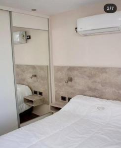 a bedroom with a white bed and a mirror at Campo Galano in Miramar