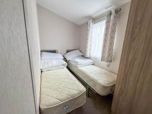 内兹岬附近沃尔顿Lovely 8 Berth Caravan With Decking To Hire At Naze Marine In Essex Ref 17030Ga的一间带窗户的小房间里有两张床 更多12张照片