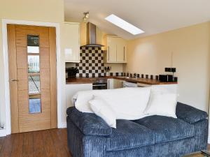 a living room with a couch in front of a kitchen at Hawthorne Cottage in Winthorpe
