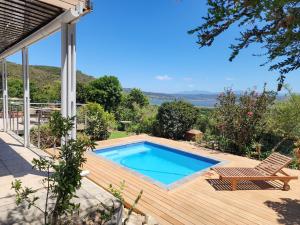 una piscina su un ponte di legno con una sedia accanto di Living Lagoon Two Apartments a Brenton-on-Sea