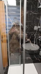 un homme est assis dans une douche avec une porte en verre dans l'établissement Adina Oase, à Rimbach 5 autres photos