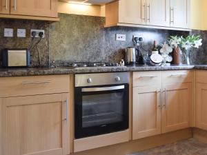 een keuken met houten kasten en een oven bij Elm Court 7 in Keswick