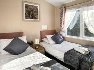 una camera da letto con due letti e una finestra di Portland a Holton Heath Altre 4 foto