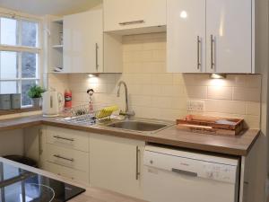 Una cocina con gabinetes blancos y un fregadero. en Jebel, en Cullen