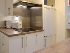 Una cocina con gabinetes blancos, un fregadero y un microondas. en Jebel, en Cullen