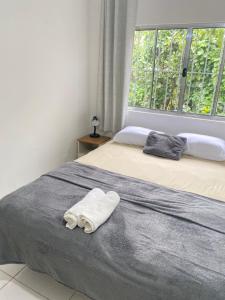 a bed with a towel on it with a window at Refúgio das Ondas I Suítes perto da praia com conforto e self check-in in Bertioga