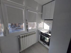 a kitchen with white cabinets and a stove and windows at Spania Studio in Craiova +3 photos