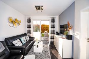 un soggiorno con divano in pelle nera e TV di Blankwasserweg 57, "Amina 2" a Grömnitzerhagen