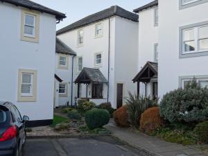 een rij witte huizen met een auto voor de deur bij 10 Elm Court in Keswick