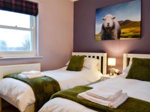 een kamer met twee bedden en een afbeelding van een schaap bij 10 Elm Court in Keswick