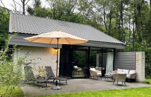 a patio with an umbrella and chairs and tables at Bosvilla Berk met een Jacuzzi in Geesbrug