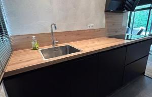 a kitchen with a sink and a wooden counter top at Bosvilla Berk met een Jacuzzi in Geesbrug
