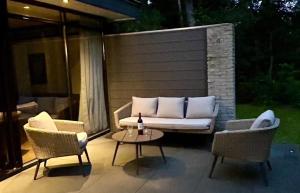 GeesbrugBosvilla Berk met een Jacuzzi的天井配有沙发、两把椅子和一张桌子 更多26张照片