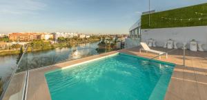 einen Pool auf einem Gebäude mit einem Fluss in der Unterkunft Ribera de Triana Hotel in Sevilla