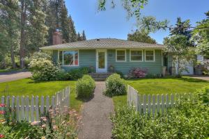 a green house with a white picket fence at Living Color Cottage in Hood River