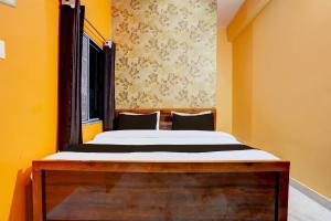 a bed in a room with yellow walls and a window at Hotel O Value in Jabalpur