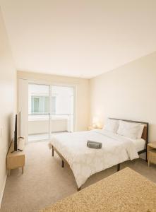 ein weißes Schlafzimmer mit einem großen Bett und einem TV in der Unterkunft Marina Del Rey Sunrise - Pool & Gym & Sauna & Cinema in Fullerton