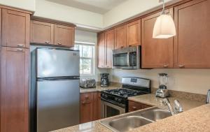 eine Küche mit Holzschränken und einem Edelstahlkühlschrank in der Unterkunft Marina Del Rey Sunrise - Pool & Gym & Sauna & Cinema in Fullerton