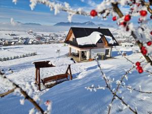 a small house in the snow with a bench at Chata Elegant in Bešeňová