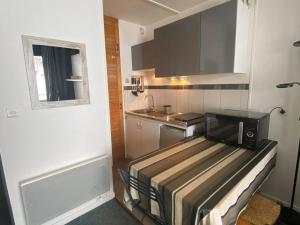 Una pequeña cocina con estufa y microondas. en Studio cosy pour 4 avec balcon et Wi-Fi, accès direct aux pistes - FR-1-602-59, en Arette