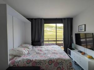Un dormitorio con una cama y una ventana grande. en Studio cosy pour 4 avec balcon et Wi-Fi, accès direct aux pistes - FR-1-602-59, en Arette