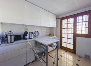 a kitchen with white cabinets and a table with chairs at AGAMARI La Mata Torrevieja sun apartment in Torrevieja +15 photos