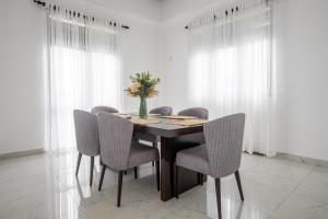 una mesa de comedor con sillas y un jarrón de flores en Elora Kandana, 