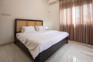 Un dormitorio con una cama grande con sábanas blancas. en Elora Kandana, 