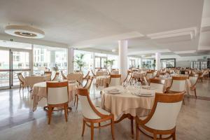 a restaurant with white tables and chairs and windows at Hotel Terme Marine Leopoldo II TERME & SPA in Marina di Grosseto