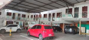 ein rotes Auto, das auf einem Parkplatz neben einem Gebäude parkt in der Unterkunft Novo Hotel & Restaurante in Manacapuru