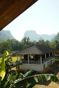 ein Haus mit einem Dach mit Bergen im Hintergrund in der Unterkunft Eco Farm Stay and Hostel in Nongkhiaw