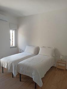 a bedroom with a bed with white sheets and a window at Ciccone's Rooms in Larino
