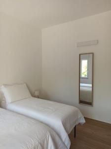 a white bedroom with two beds and a mirror at Ciccone's Rooms in Larino +8 photos