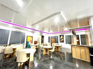 un comedor con mesas, sillas y luces púrpuras en The Grand Hotel Ciamis, en Ciamis