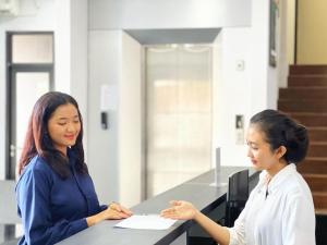 dos mujeres de pie en un mostrador hablando en The Grand Hotel Ciamis, en Ciamis