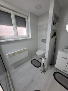 a white bathroom with a toilet and a window at Aki Land in Mladenovac