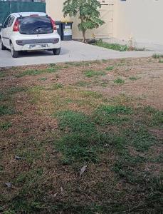 Un coche blanco aparcado junto a un campo de hierba. en L'escale Foyalaise - wifi, clim, jardin créole, parking privatif, en Fort-de-France