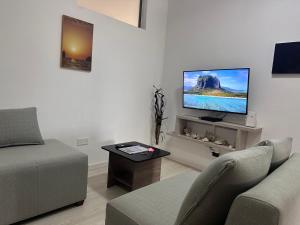 a living room with a couch and a flat screen tv at Suite Sky and Sea in Flic-en-Flac