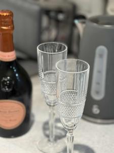 麦克尔斯菲尔德Wonky 2 A Cosy Hideaway in the Heart of Cheshire的两杯空酒杯,坐在一瓶葡萄酒旁边