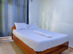 a bed with white sheets and pillows on it at Romanesca Motel in Rubavu