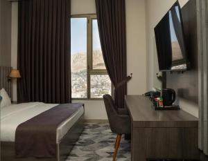 a hotel room with a bed and a desk and window at Wan Hotel in Duhok +26 photos