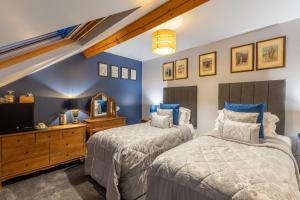 two beds in a bedroom with blue walls at Brooklands 5 Star Guest House in Penrith